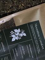 Tea packaging with 'Moontime Comfort' label and herbal illustration on a dark background.