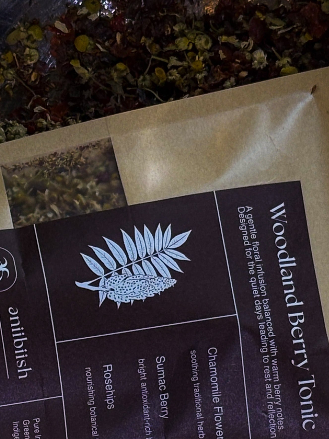 Tea packaging with 'Woodland Berry Tonic' label and herbal illustration.