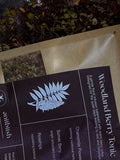 Tea packaging with 'Woodland Berry Tonic' label and herbal illustration.